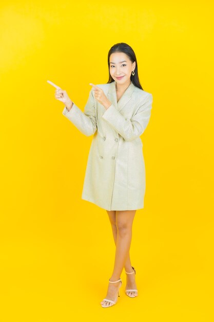 Portrait belle jeune femme asiatique sourit et pointe vers la gauche sur le mur de couleur