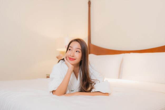 Portrait belle jeune femme asiatique sourit reposant sur le lit à l'intérieur de la chambre