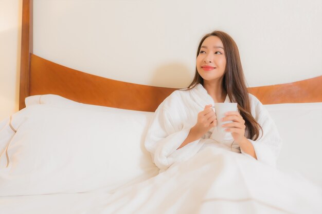 Portrait belle jeune femme asiatique sourit reposant sur le lit à l'intérieur de la chambre