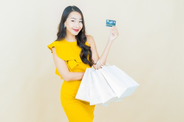 Portrait belle jeune femme asiatique sourit avec sac à provisions sur mur beige
