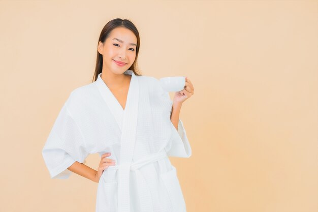 Portrait belle jeune femme asiatique avec une tasse de café sur beige