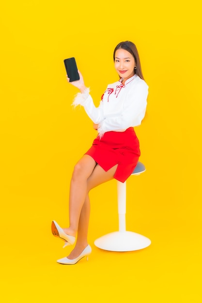 Portrait belle jeune femme asiatique avec téléphone mobile intelligent sur jaune