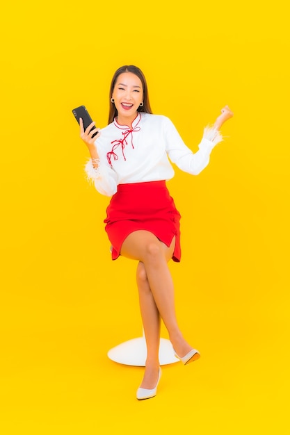 Portrait belle jeune femme asiatique avec téléphone mobile intelligent sur jaune
