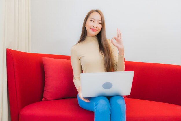 Portrait de la belle jeune femme asiatique utilise un ordinateur portable sur un canapé à l'intérieur du salon