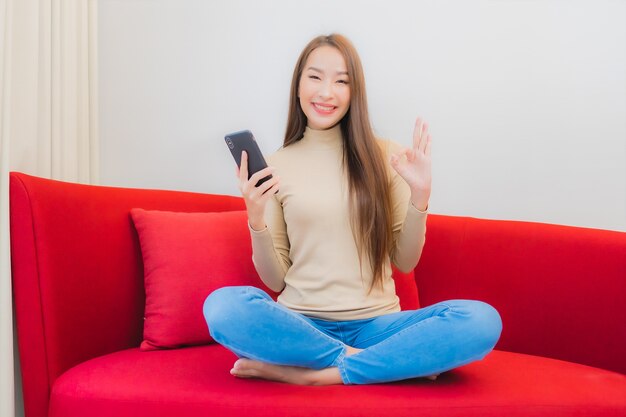 Portrait de la belle jeune femme asiatique utilise le smartphone sur le canapé à l'intérieur du salon