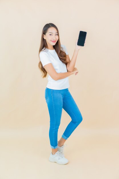 Portrait belle jeune femme asiatique utilise un téléphone mobile intelligent sur beige