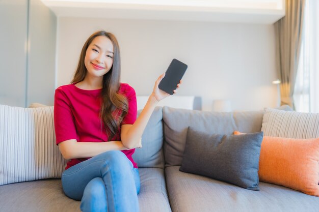 Portrait belle jeune femme asiatique utilise un téléphone mobile intelligent sur le canapé