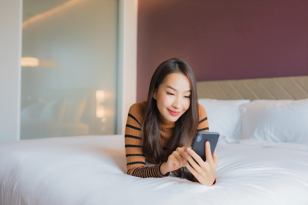 Portrait belle jeune femme asiatique utilise un téléphone mobile intelligent sur le lit
