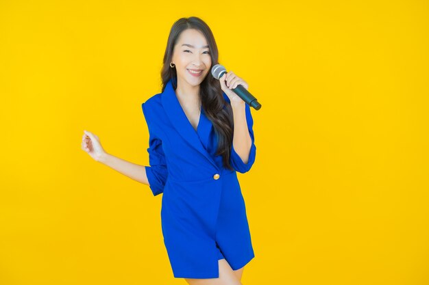 Portrait belle jeune femme asiatique utiliser un microphone pour chanter sur jaune