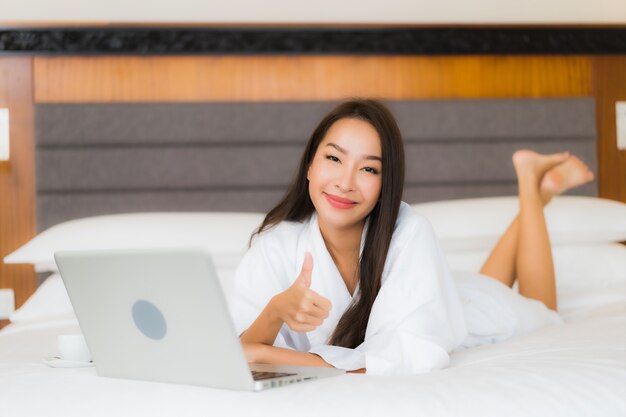 Portrait belle jeune femme asiatique utiliser un ordinateur portable sur le lit à l'intérieur de la chambre