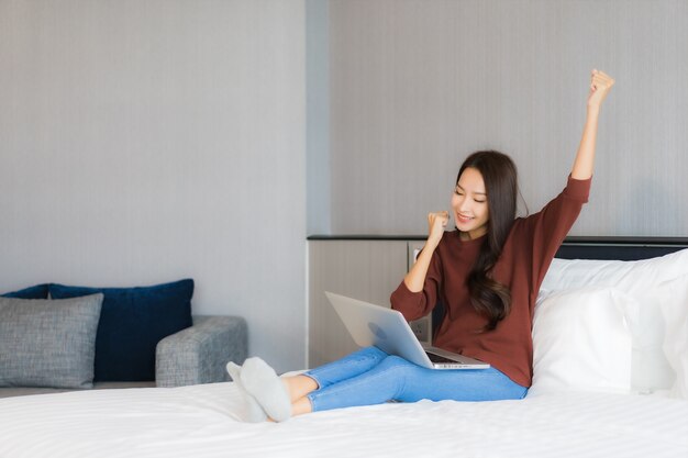 Portrait belle jeune femme asiatique utiliser un ordinateur portable sur le lit à l'intérieur de la chambre