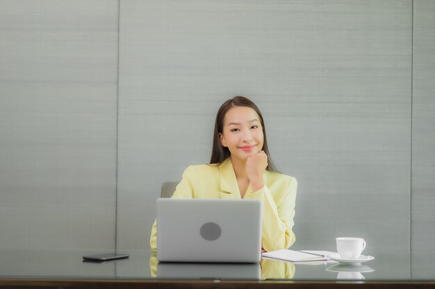 Portrait belle jeune femme asiatique utiliser un ordinateur portable avec un téléphone mobile intelligent sur la table de travail à l'intérieur de la salle