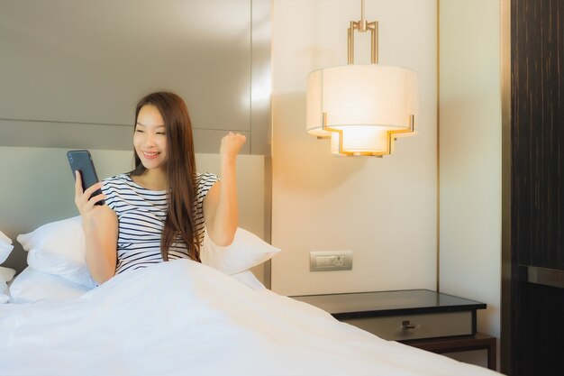 Portrait belle jeune femme asiatique utiliser un téléphone mobile intelligent sur le lit à l'intérieur de la chambre