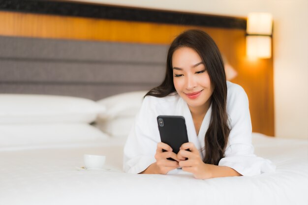 Portrait belle jeune femme asiatique utiliser un téléphone mobile intelligent sur le lit à l'intérieur de la chambre