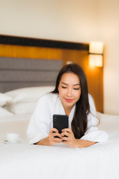 Portrait belle jeune femme asiatique utiliser un téléphone mobile intelligent sur le lit à l'intérieur de la chambre