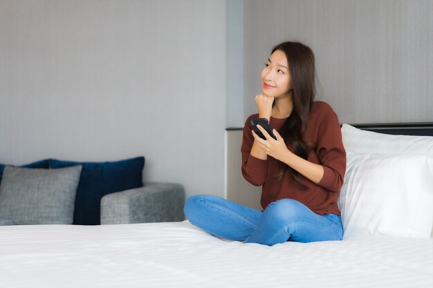 Portrait belle jeune femme asiatique utiliser un téléphone mobile intelligent sur le lit à l'intérieur de la chambre