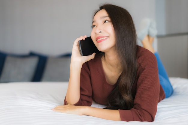 Portrait belle jeune femme asiatique utiliser un téléphone mobile intelligent sur le lit à l'intérieur de la chambre