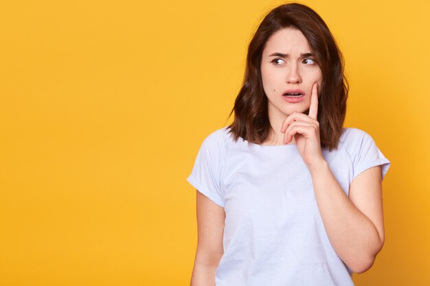 Portrait de la belle jeune femme brune pensive dans des vêtements légers à côté