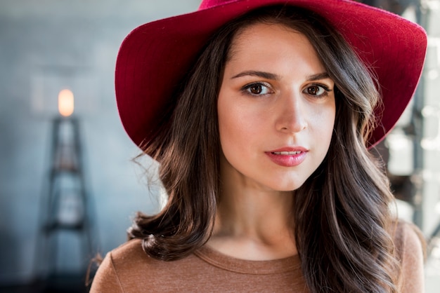 Portrait d&#39;une belle jeune femme avec un chapeau rose sur la tête en regardant la caméra