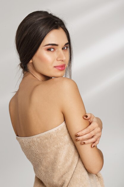 Portrait d'une belle jeune femme chic après spa debout couvert de serviette.
