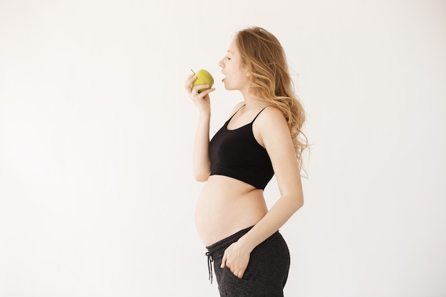 Portrait de la belle jeune femme enceinte aux cheveux blonds à domicile avec ventre ouvert