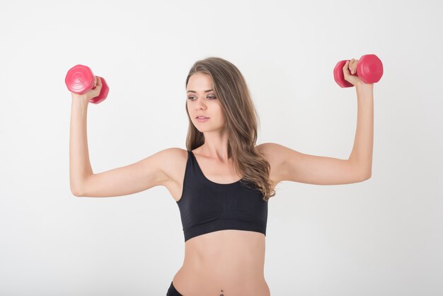 Portrait de la belle jeune femme faisant des exercices physiques avec des haltères