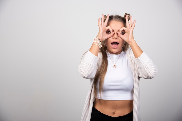 Photo gratuite portrait d'une belle jeune femme faisant un geste de lunettes.