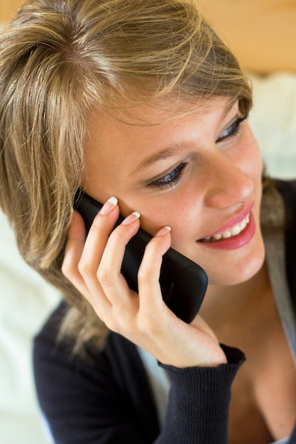 Portrait d&#39;une belle jeune femme à la maison avec mobile.