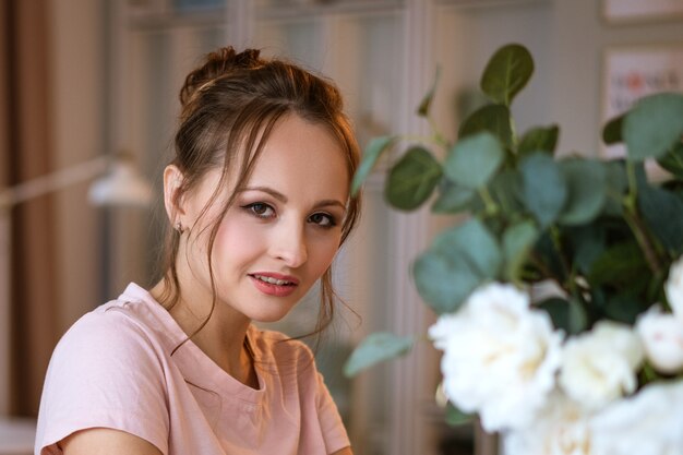 Portrait d'une belle jeune femme à la maison, un vase de fleurs