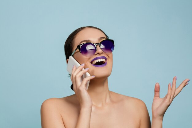 Portrait de la belle jeune femme avec maquillage lumineux isolé sur mur bleu