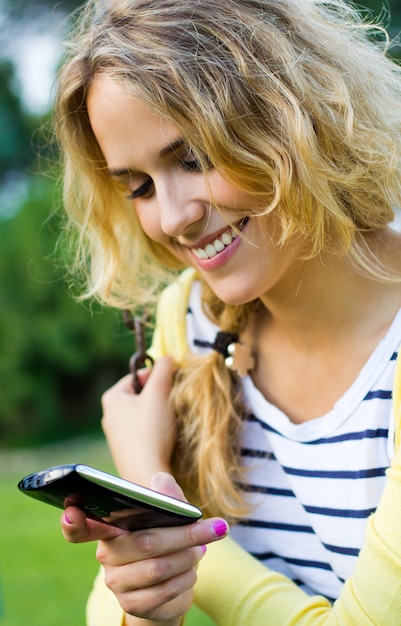 Portrait d&#39;une belle jeune femme avec un mobile au parc