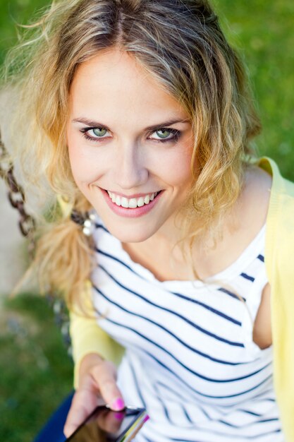 Portrait d&#39;une belle jeune femme avec un mobile au parc