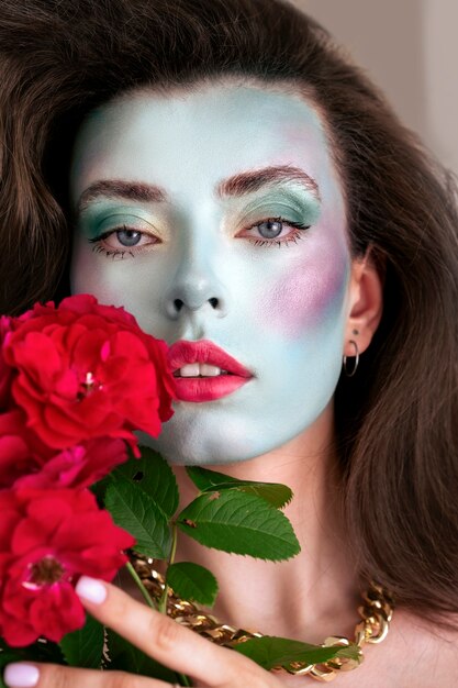 Portrait d'une belle jeune femme avec de la peinture faciale et des fleurs