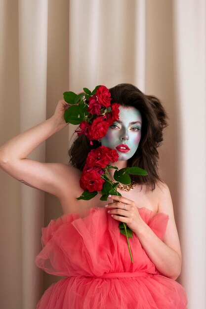 Portrait d'une belle jeune femme avec de la peinture faciale et des fleurs