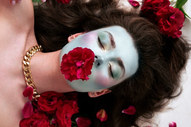 Portrait d'une belle jeune femme avec de la peinture faciale et des fleurs