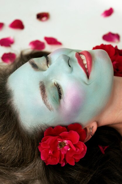 Portrait d'une belle jeune femme avec de la peinture faciale et des fleurs