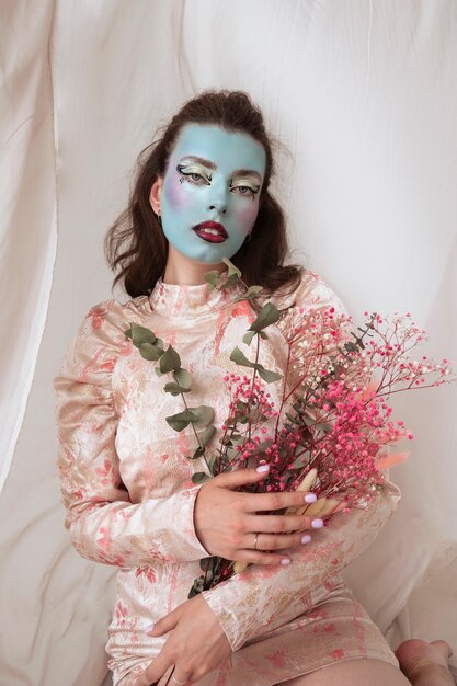 Portrait d'une belle jeune femme avec de la peinture faciale et des fleurs