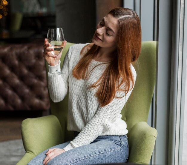 Photo gratuite portrait de la belle jeune femme regardant un verre de vin