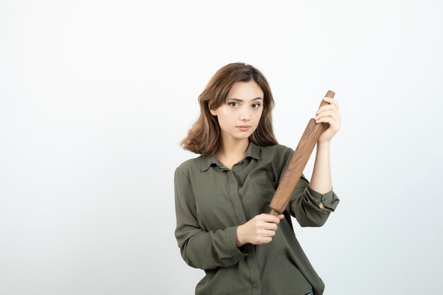 Portrait de belle jeune femme avec un rouleau à pâtisserie en bois debout. Photo de haute qualité