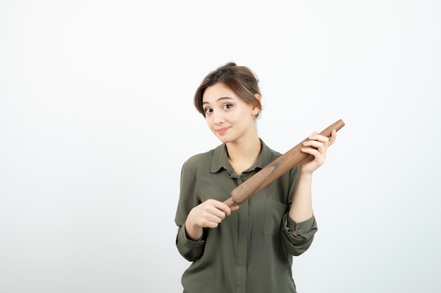 Portrait de belle jeune femme avec un rouleau à pâtisserie en bois debout. Photo de haute qualité