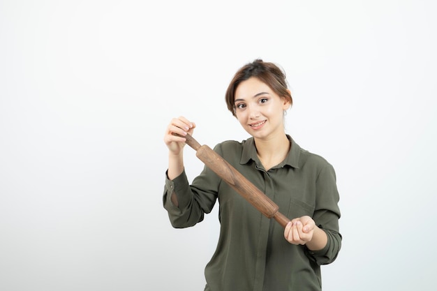 Portrait de belle jeune femme avec un rouleau à pâtisserie en bois debout. Photo de haute qualité