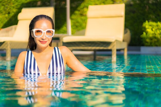 Portrait belle jeune femme se détendre sourire loisirs en vacances autour de la piscine dans l'hôtel de villégiature