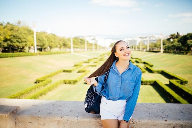 Portrait d'une belle jeune femme souriante dans le parc de la ville d'été vert