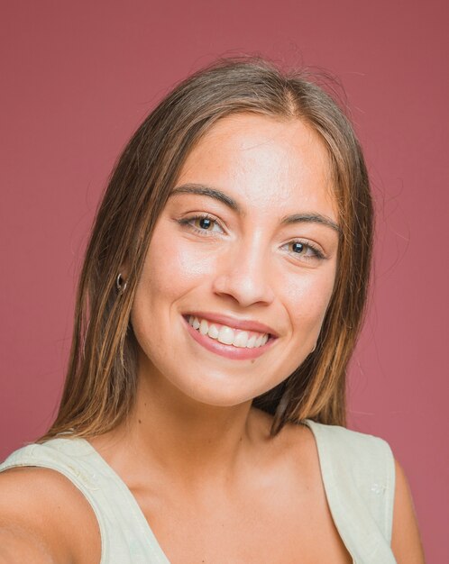 Portrait de belle jeune femme souriante sur fond coloré