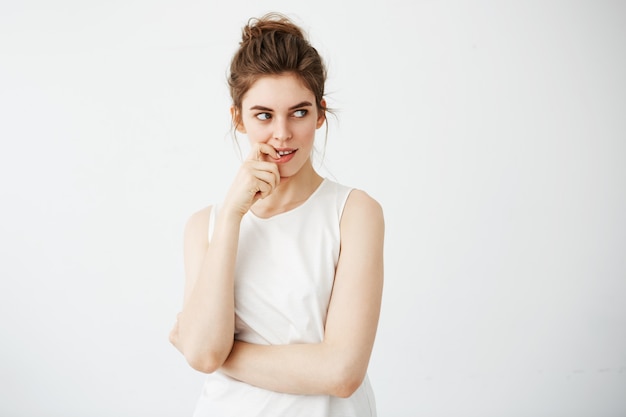 Portrait de la belle jeune femme souriante pensant rêver toucher son menton.