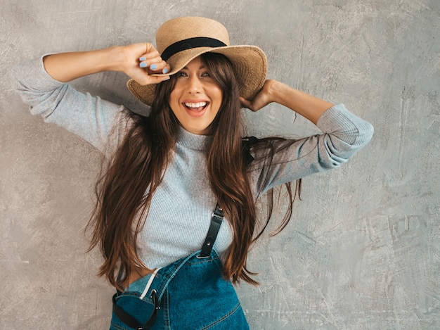 Portrait De La Belle Jeune Femme Souriante à La Recherche. Fille à La Mode Dans Des Vêtements De Salopette D'été Décontractée Et Un Chapeau.