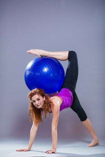 Portrait de la belle jeune femme sportswear travaillant sur fond gris. Fit fille sportive faisant du yoga avancé, pilates, fitness.