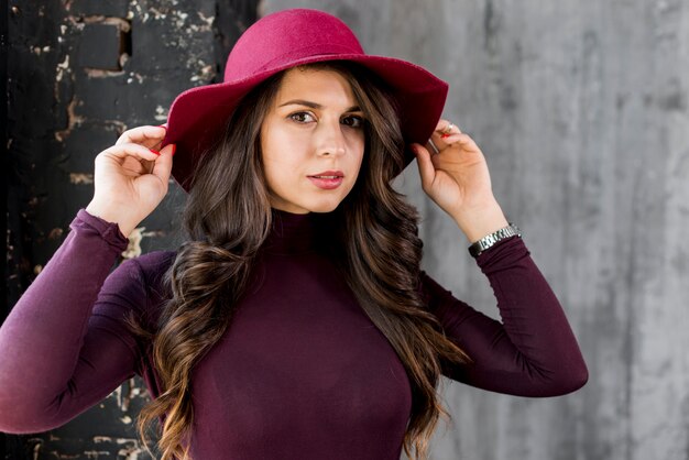 Portrait d&#39;une belle jeune femme tenant un chapeau sur la tête avec sa main