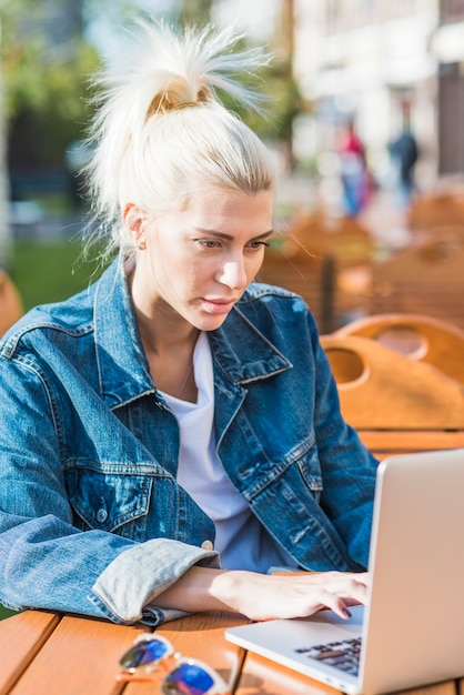 Portrait d&#39;une belle jeune femme travaillant sur un ordinateur portable sur un bureau en bois