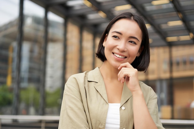 Photo gratuite portrait d'une belle jeune femme vêtue de vêtements décontractés souriante posant à l'extérieur dans une rue vide à proximité